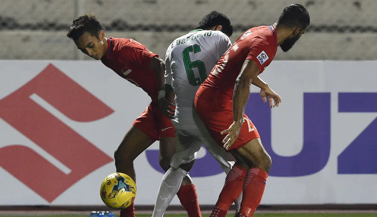 Evan Dimas (tengah) dikawal ketat pemain Singapura saat laga di Piala AFF 2016, Manila, Jumat (25/11). Timnas Indonesia memastikan diri ke semifinal Piala AFF 2016 usai mengalahkan Singapura 2-1. (AFP PHOTO / Ted Aljibe)