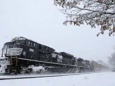 Sebuah kereta barang melaju saat badai salju di Manville, New Jersey (21/3). Badai salju yang melanda sebagian Amerika Serikat telah membawa salju dan angin kencang. (AP/Julio Cortez)