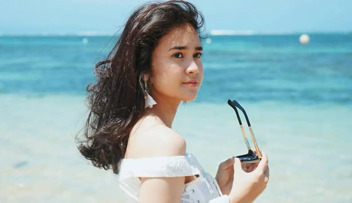 Michelle Ziudith perempuan berusia 25 tahun ini tampil begitu menawan saat berlibur di pantai. Ia memakai pakaian putih dan memegan kacamata. Gaya penampilannya yang simpel tapi menawan ini tuai pujian. (Liputan6.com/IG/@michelleziu)