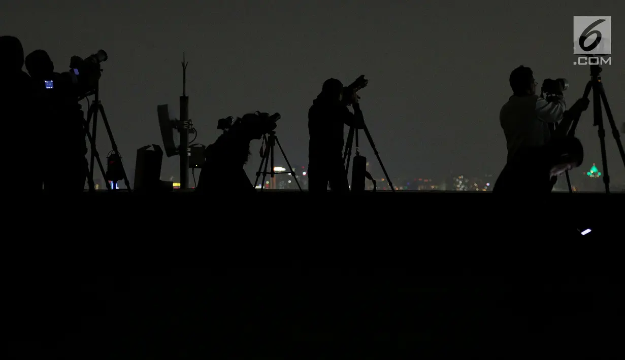 Pecinta fotografi mengabadikan fenomena gerhana "Super Blue Blood Moon" di atas Gedung MPR/DPR Senayan, Jakarta, Rabu Malam (31/1). (Liputan6.com/Johan Tallo)