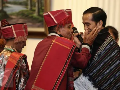 Pemangku Hutan Adat dari Tombak Haminjon (Kemenyan) Provinsi Sumatera Utara mengalungkan kain ulos kepada Presiden Joko Widodo (Jokowi) usai pencanangan pengakuan Hutan Adat di Istana Negara, Jakarta, Jumat (30/12). (Liputan6.com/Faizal Fanani)