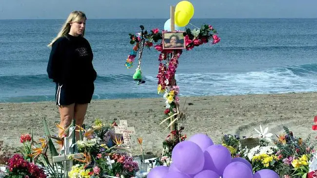 Seorang wanita berdiri di tugu peringatan dadakan di pantai California setelah jatuhnya Alaska Airlines 261. (Sumber AFP)
