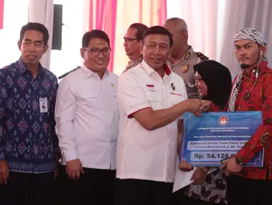 Menko Polhukam Wiranto didampingi Ketua Lembaga Perlindungan Saksi dan Korban (LPSK) Abdul Haris Semendawai memberi kompensasi kepada sejumlah perwakilan korban terorisme di Kantor LPSK, Jakarta, Kamis (6/9). (Liputan6.com/Faizal Fanani)
