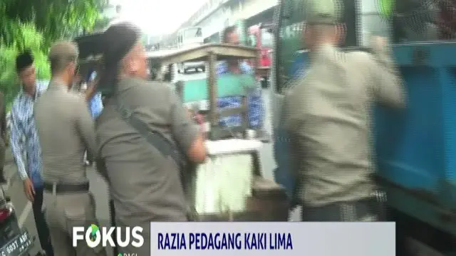 Pedagang sayur keliling ini berusaha keras mempertahankan gerobak dagangannya saat akan diangkut ke truk Satpol PP.