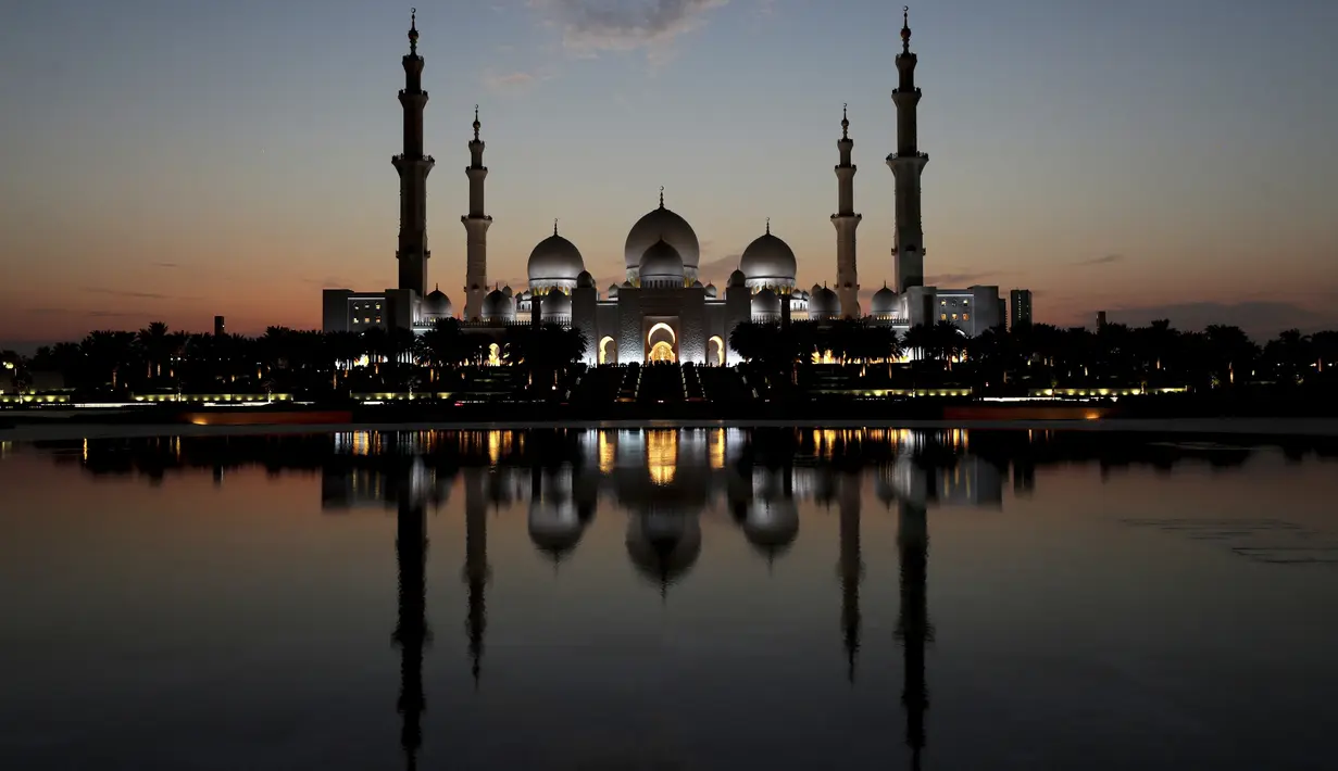 Matahari terbenam di belakang Masjid Agung Sheikh Zayed di Abu Dhabi, Uni Emirat Arab (8/11/2019). Masjid Agung Sheikh Zayed di bangun pada tahun 1996 dengan 82 kubah bergaya Maroko dan semuanya dihias dengan batu pualam putih. (AFP Photo/Kamran Jebreili)