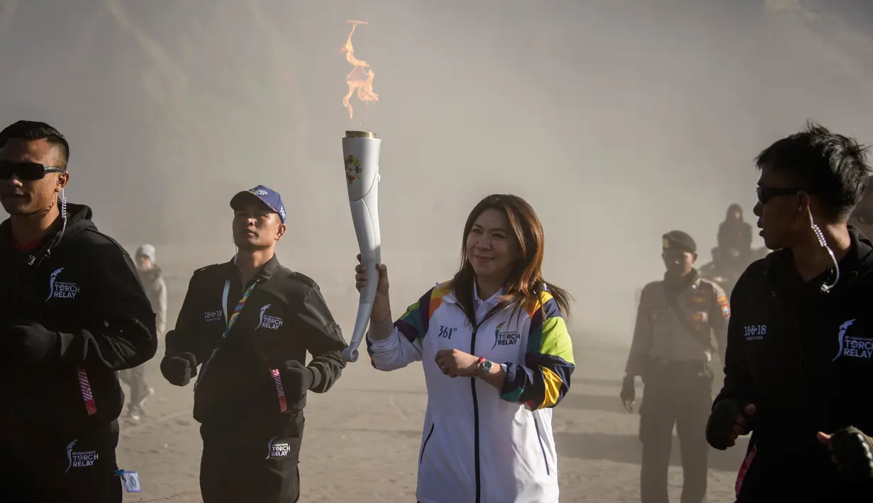 Legenda bulu tangkis Indonesia, Susi Susanti (dua kanan) membawa obor Asian Games 2018 di Gunung Bromo, Probolinggo, Jawa Timur, Sabtu (21/7). Selanjutnya obor Asian Games 2018 akan dibawa menuju Banyuwangi. (JUNI KRISWANTO/AFP)