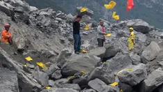 Keluarga korban melemparkan kertas ritual untuk menenangkan arwah orang yang tewas di lokasi tanah longsor di desa Xinmo, Sichuan, China (25/6). Sekitar 118 orang hilang diduga tertimbun bebatuan akibat longsor ditempat tersebut. (AP Photo / Ng Han Guan)