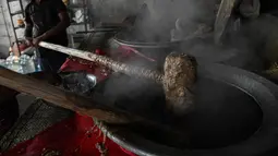 Koki katering menyiapkan hidangan bernama 'rebusan daging kambing Haleem' dalam peralatan besar untuk dijual kepada umat Muslim untuk berbuka puasa selama Ramadhan di Chennai (20/4/2022). Haleem adalah sajian favorit yang cukup populer, terutama saat bulan Ramadhan dan Muharram. (AFP/Arun Sankar)