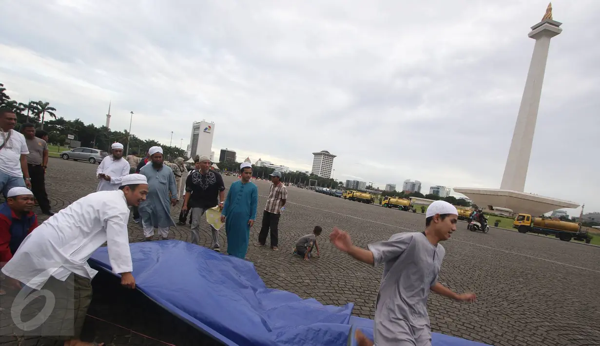 Warga mempersiapkan kelengkapan aksi damai 2 Desember di Monas, Jakarta, Kamis (1/12). Jelang aksi damai, sejumlah persiapan mulai dilakukan, seperti panggung, baris untuk Salat Jumat, hingga pengamanan dari kepolisian. (Liputan6.com/Immanuel Antonius)
