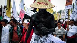 Seorang massa petani dari berbagai provinsi melakukan aksi teatrikal saat menggelar demonstrasi di kawasan Medan Merdeka, Jakarta, Selasa (27/9). Aksi menyuarakan aspirasi petani itu digelar dalam rangka Hari Tani Nasional. (Liputan6.com/Faizal Fanani)