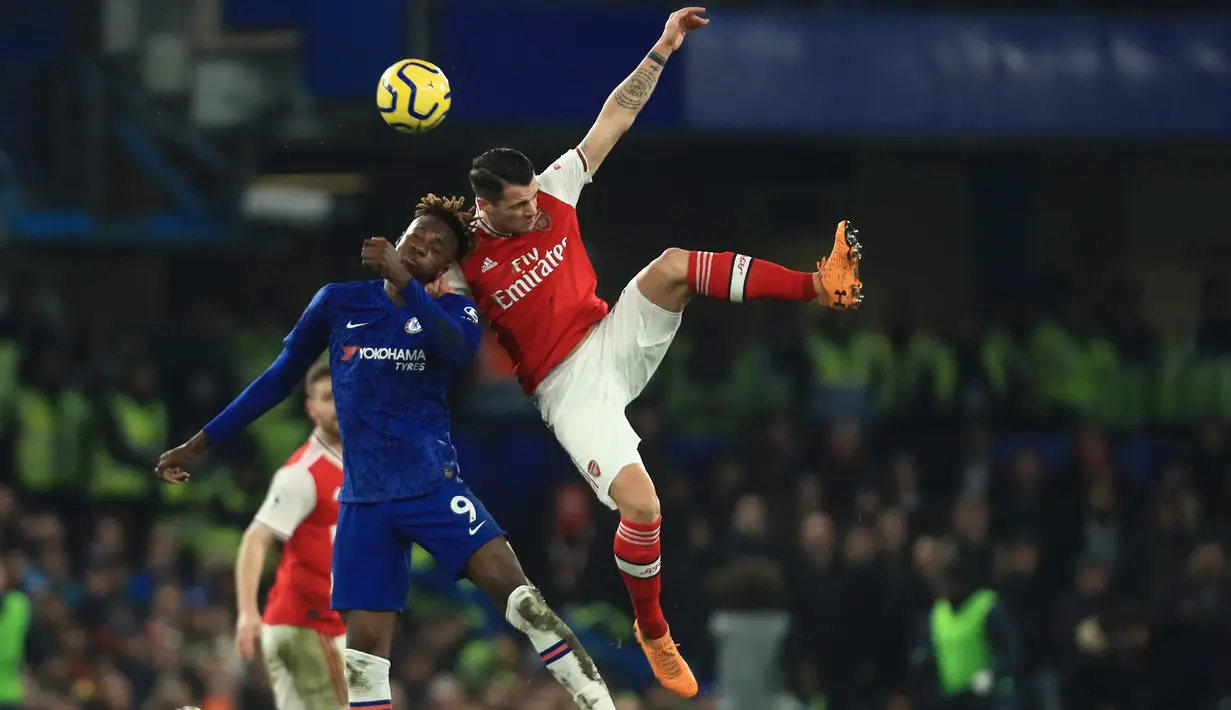 Striker Chelsea, Tammy Abraham berebut bola dengan penyerang Arsenal, Gabriel Martinelli pada lanjutan pertandingan Liga Inggris di Stamford Bridge, Selasa (21/1/2020). Chelsea gagal memetik hasil maksimal usai ditahan Arsenal dengan skor 2-2. (AP Photo/Leila Coker)