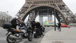 Polisi memeriksa dokumen pengemudi kendaraan saat lockdown di depan Menara Eiffel, Paris, Prancis, Rabu (18/3/2020). Pemerintah Prancis memberlakukan denda 135 Euro bagi warga keluar rumah tanpa pernyataan tertulis yang dibenarkan. (Ludovic MARIN/AFP)