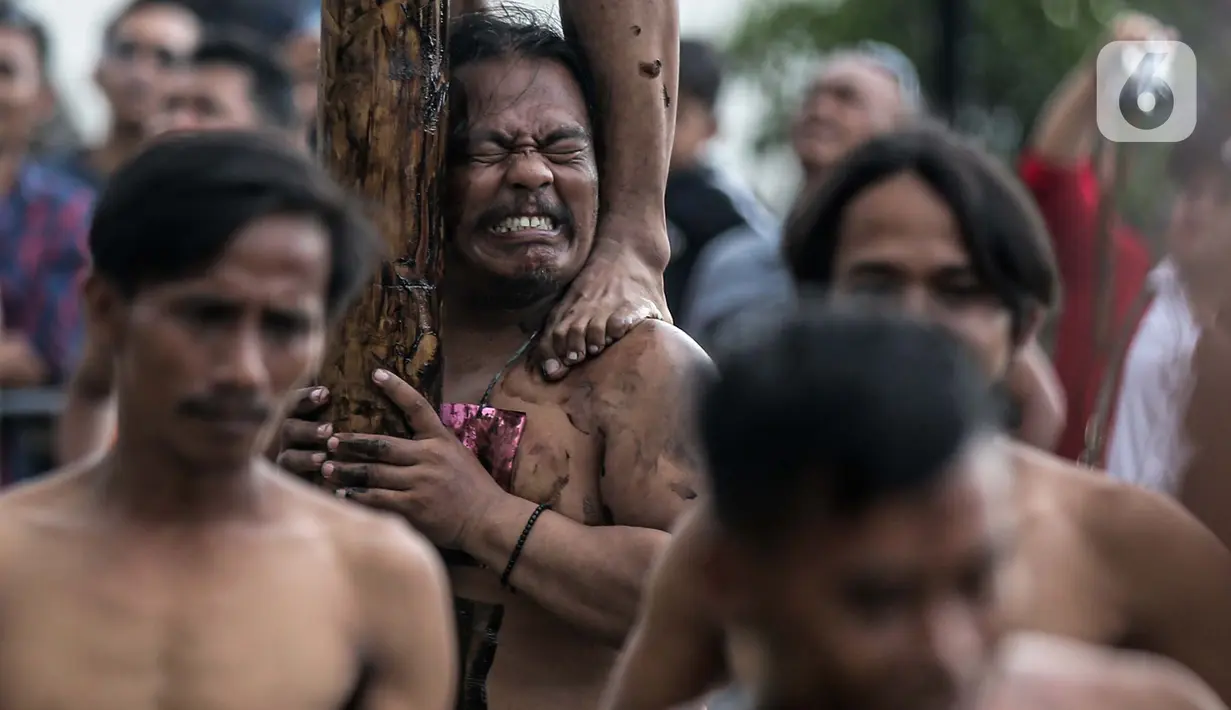 Peserta lomba panjat pinang massal menahan berat dari teman- tamannya yang memanjat pinang di Pantai Festival Ancol, Jakarta, Rabu (17/8/2022). Sebanyak 45 pohon pinang siap dipanjat oleh pengunjung di Pantai Festival Ancol  untuk memeriahkan Hari Ulang Tahun (HUT) Ke-77 Republik Indonesia. (Liputan6.com/Faizal Fanani)