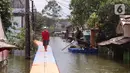 Warga berjalan melintasi jembatan apung saat banjir melanda Perumahan Periuk Damai, Tangerang, Banten, Selasa (23/2/2021). Adanya jembatan apung mempermudah warga saat melintasi banjir setinggi 2,5 meter di tempat tersebut. (Liputan6.com/Angga Yuniar)