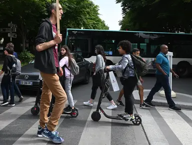 Arshavir Grigoryan yang memiliki tinggi tubuh 2 meter 33 centimeter berjalan saat berkumpul di Champs-Elysees Avenue di Paris, Prancis (14/6/2019). Sambil membawa poster, belasan pria tertinggi dunia berkumpul pada akhir pekan di Champs-Elysees Avenue. (AFP Photo/Dominique Faget)