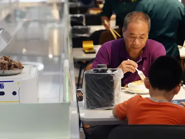 Pengunjung menunggu makanan yang akan diantarkan oleh robot di restoran Robot.He milik Alibaba di Shanghai, 30 Juli 2018. Robot pintar yang sebesar oven microwave bertugas menerima pesanan dan mengantarkan makanan di atas nampan kepada para tamu. (AFP)