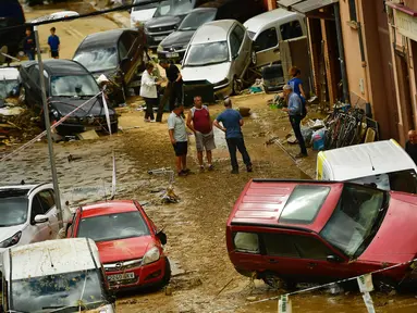 Warga berkumpul di jalan dekat mobil yang rusak setelah banjir bandang menerjang Tafalla, Spanyol, Selasa (9/7/2019). Hujan deras menyebabkan dua sungai meluap dan menimbulkan banjir bandang. (AP Photo/Alvaro Barrientos)