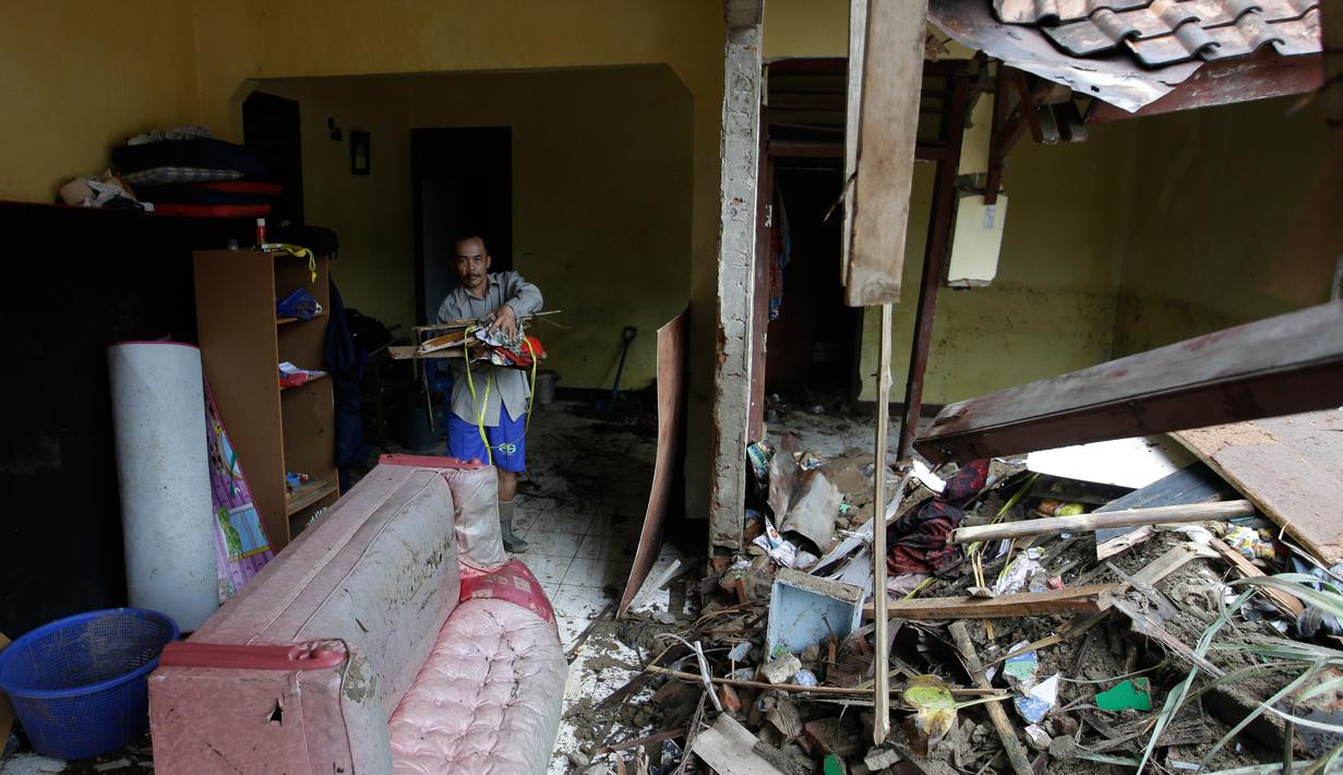 Warga lokal Alimin membersihkan puing-puing dari rumahnya setelah tsunami di Carita, Banten, Kamis, (27/12). Ratusan orang tewas akibat tsunami Selat Sunda akhir pekan lalu. (AP Photo/Achmad Ibrahim)