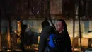 Sementara, Layanan Darurat Negara Ukraina menyampaikan bahwa kebakaran kini telah terkendali, sementara proses evakuasi dan pencarian korban tetap dilakukan. Tampak dalam foto, seorang perempuan menggendong anaknya di depan bangunan tempat tinggal yang terbakar setelah serangan Rusia di Zaporizhzhia, Ukraina, Rabu 26 November 2025. (AP Photo/Kateryna Klochko)