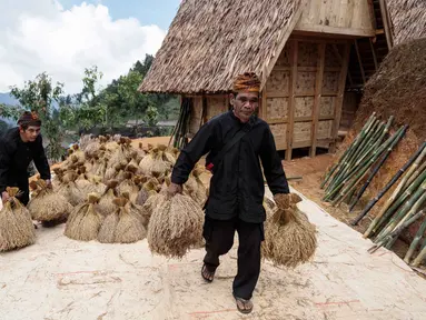 Warga bersiap meletakkan tumpukan padi di lumbung kayu tradisional di atas panggung, yang dikenal masyarakat setempat sebagai leuit, dalam perayaan panen Seren Taun di Sukabumi, Jawa Barat, pada Minggu 5 Oktober 2025. (Aditya AJI/AFP)