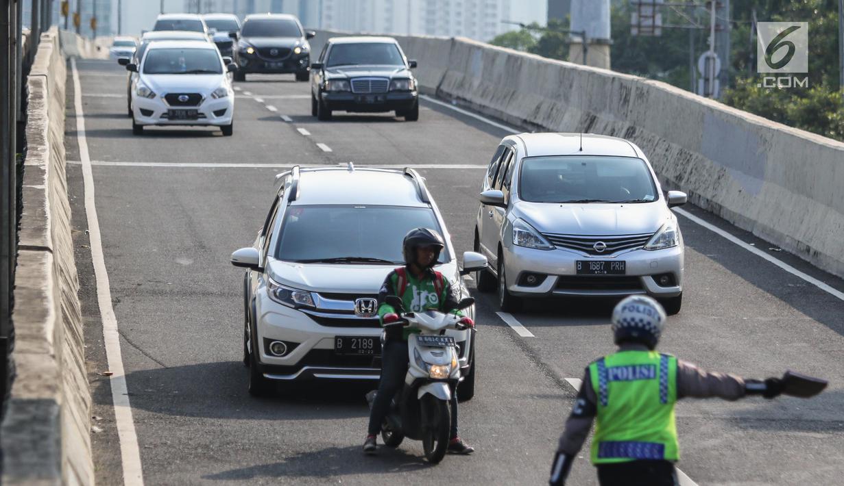 Petugas kepolisian memberhentikan pengemudi ojek online yang melintasi JLNT Kampung Melayu-Tanah Abang, Jakarta, Selasa (25/7). Polisi terus merazia kendaraan roda dua yang melanggar rambu larangan melintas di JLNT tersebut. (Liputan6.com/Faizal Fanani)