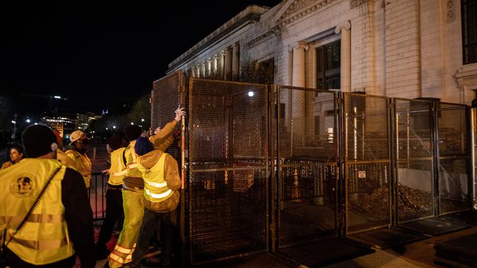 Pekerja memasang pagar besi di pintu masuk Gedung Putih mengantisipasi kerusuhan menjelang Pilpres Amerika Serikat di Washington DC, Senin (2/11/2020). Sebagai persiapan kemungkinan ada aksi terorisme atau protes massa, Gedung Putih membangun pagar baru. (Chris McGrath/Getty Images/AFP)