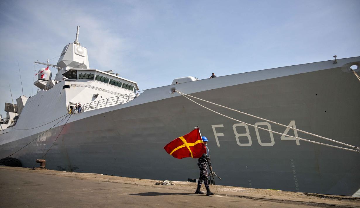 Personel Tentara Nasional Indonesia (TNI) Angkatan Laut (AL) membawa bendera sinyal maritim internasional berjalan di samping kapal perang Kerajaan Belanda HNLMS De Ruyter di pelabuhan Tanjung Perak, Surabaya, Jawa Timur pada Kamis 14 Mei 2026. (JUNI KRISWANTO/AFP)