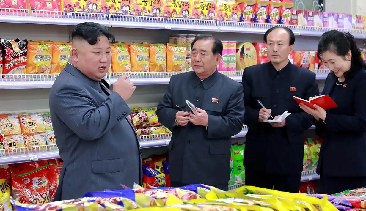 Pemimpin Korea Utara, Kim Jong-un berbincang dengan stafnya ketika berada di toko makanan saat mengunjungi Taesong Department Store setelah dibuka untuk umum di Korea Utara (8/4). (KCNA VIA AFP Photo)