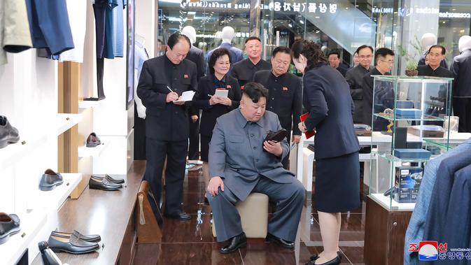 Pemimpin Korea Utara, Kim Jong-un melihat sepatu saat mengunjungi Taesong Department Store, setelah dibuka untuk umum di Korea Utara (8/4). (KCNA VIA AFP Photo)
