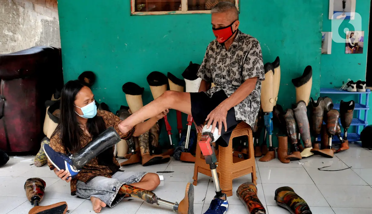 Ronald Regen (33), perajin yang juga penyandang disabilitas memasangkan kaki palsu ke pelanggan di Dusun IV Rawailat, Desa Dayeuh, Cileungsi, Bogor, Jawa Barat, Selasa (29/3/2022). UMKM kaki palsu yang sempat bangkrut akibat pandemi COVID-19 mulai bangkit sejak awal tahun. (merdeka.com/Arie Basuki)