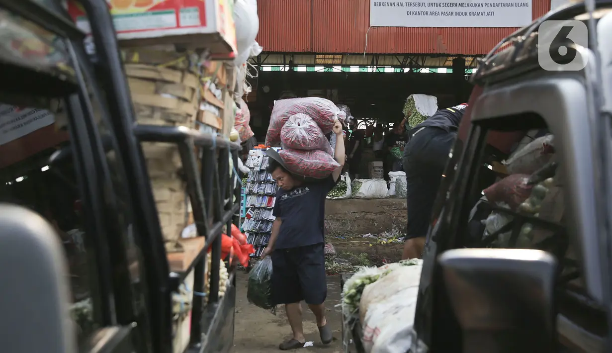 Seorang pria memanggul plastik berisi cabai merah di pasar induk Kramat Jati, Jakarta, Minggu (12/4/2020). Kegiatan di pasar tersebut berjalan normal selama pandemi COVID-19, namun penjual dan pekerja masih terlihat belum mengenakan masker. (Liputan6.com/Johan Tallo)