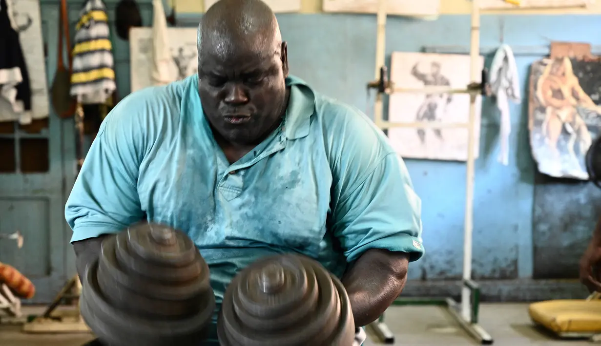 Seorang binaragawan mengangkat beban saat berolahraga di gym Kaloleni, di Nairobi, Kenya (9/1). (AFP Photo/Simon Maina)