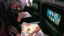 Pengunjung menonton film sembari menikmati makanan di kelas bisnis selama makan siang perdana di Restaurant A380 @Changi di atas pesawat Airbus A380, di Bandara Internasional Changi, 24 Oktober 2020. Singapore Airlines mengubah salah satu pesawatnya menjadi sebuah restoran mewah. (ROSLAN RAHMAN/AFP)