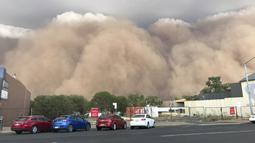 Sejumlah mobil terparkir saat badai debu mengepul di sebuah jalan di Dubbo, Australia, 400 km (248 mil) barat Sydney (19/1/2020). Hembusan angin 107 kilometer per jam (66 mph) dicatat di Dubbo saat badai debu turun ke atas kota. (Ian Harris via AP)