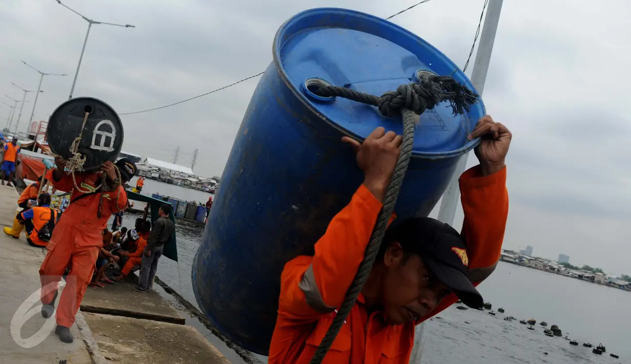 Petugas Basarnas membawa drum kosong untuk mengangkat bangkai kapal Zahro Express di Pelabuhan Muara Angke, Jakarta, Rabu (4/1). Puluhan drum kosong dipasang di sekeliling bangkai kapal untuk mengangkat kapal perlahan-lahan. (Liputan6.com/Gempur M Surya)