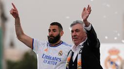 Pelatih Real Madrid, Carlo Ancelotti dan penyerang Karim Benzema melambai kepada suporter saat merayakan trofi La Liga Spanyol di alun-alun Plaza Cibeles di Madrid pada 30 April 2022. Real Madrid mengamankan gelar La Liga ke-35  setelah kemenangan kandang 4-0 atas Espanyol. (AFP/Oscar Del Pozo)