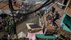 Warga menyaksikan aksi seorang pengendara sepeda saat mengikuti balapan Urban Bike Inder Medellin di gubuk comuna 1 di Medellin, Antioquia department, Kolombia (19/11). (AFP Photo/Joaquin Sarmiento)