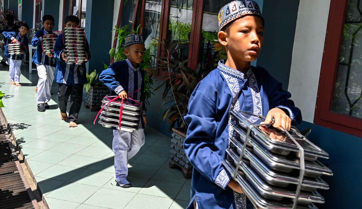 Para siswa membawa nampan berisi makanan, yang disediakan oleh program Makan Bergizi Gratis (MBG), ke kelas masing-masing di sebuah sekolah dasar di Banda Aceh pada Kamis 30 Oktober 2025. Program MBG bertujuan meningkatkan gizi dan kualitas sumber daya manusia. (CHAIDEER MAHYUDDIN/AFP)