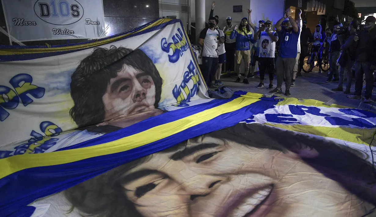 Para penggemar mantan bintang sepak bola Argentina, Diego Maradona berkumpul di luar rumah sakit tempatnya akan menjalani operasi di Olivos, Buenos Aires, Selasa (3/11/2020). Diego Maradona menjalani operasi hematoma subdural atau pembekuan darah di otak. (JUAN MABROMATA / AFP)