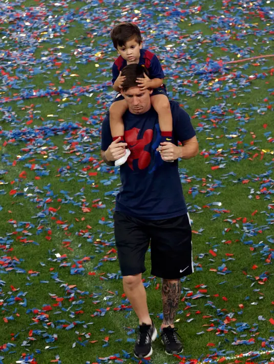 Penyerang Barcelona, Lionel Messi bersama anaknya saat parade kemenangan di stadion Camp Nou, Spanyol (7/6/2015). Barcelona untuk kelima kalinya meraih piala liga Champions usai mengalahkan Juventus 3-1 di Stadion Olympic. (REUTERS/Gustau Nacarino)