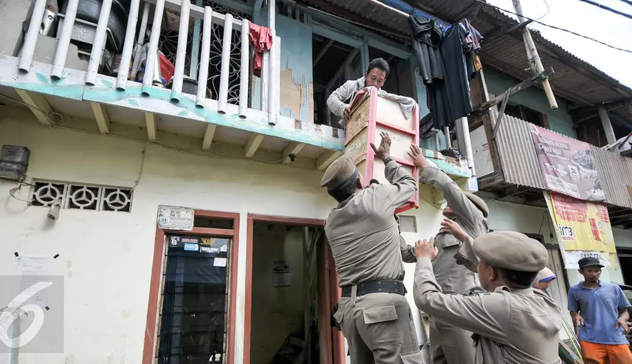 Warga dibantu petugas Satpol PP mengemasi barang milik mereka di kawasan Bukit Duri, Jakarta, Rabu (28/9). Pemprov DKI Jakarta menyediakan 400 unit Rusun Rawa Bebek untuk warga yang terkena penertiban. (Liputan6.com/Yoppy Renato)