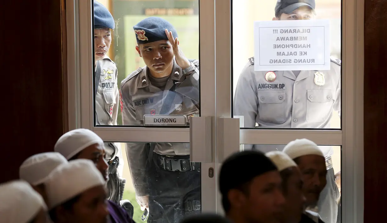 Petugas polisi mengintip jalannya sidang permohonan peninjauan kembali (PK) yang diajukan terpidana kasus terorisme Abu Bakar Ba'asyir di PN Cilacap, Jawa Tengah, (12/1/2016). (REUTERS/Darren Whiteside)
