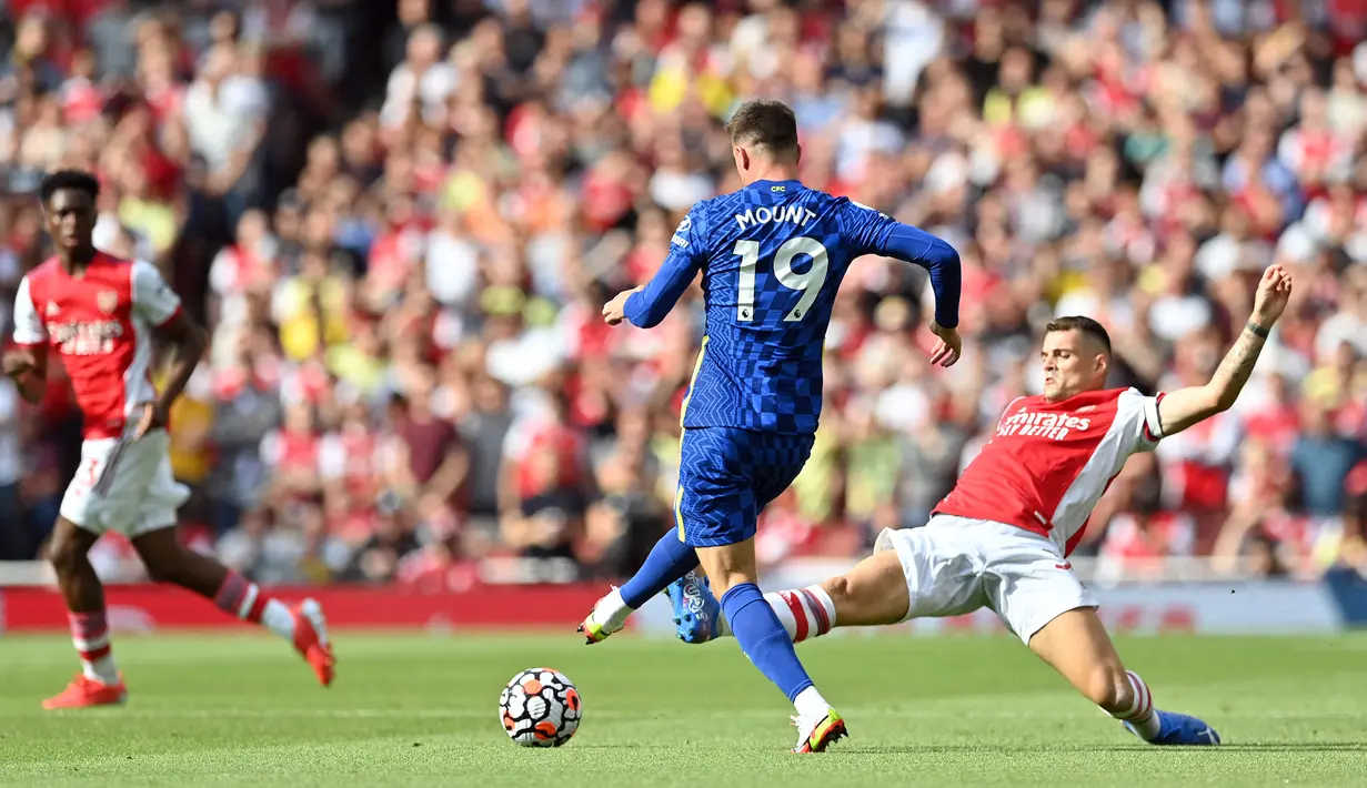 Pemain Arsenal Granit Xhaka (kanan) meluncur untuk menjegal gelandang Chelsea Mason Mount (tengah) pada pertandingan Liga Inggris di Emirates Stadium, London, Inggris, 22 Agustus 2021. Chelsea menang 2-0. (JUSTIN TALLIS/AFP)