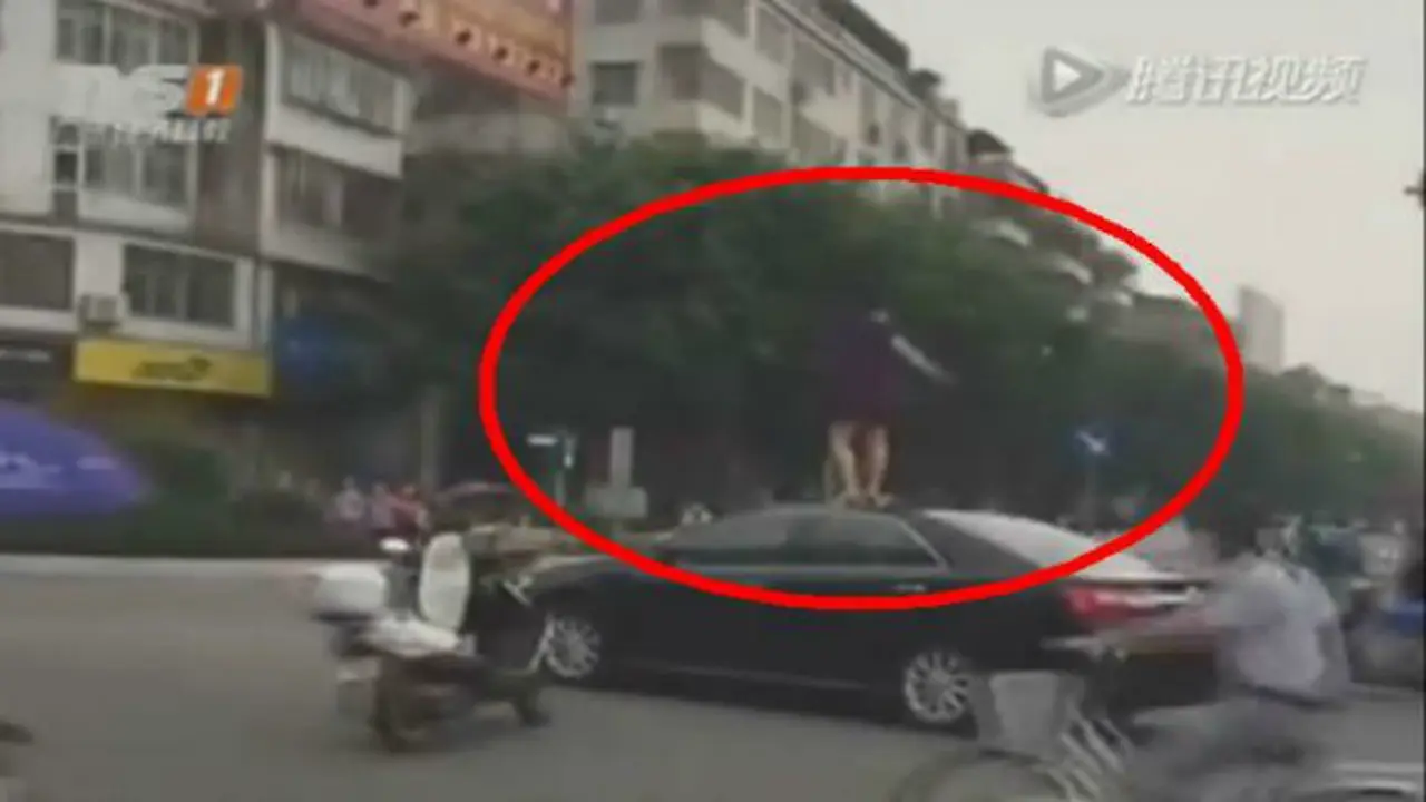 Wanita menari di atas mobil di perempatan.