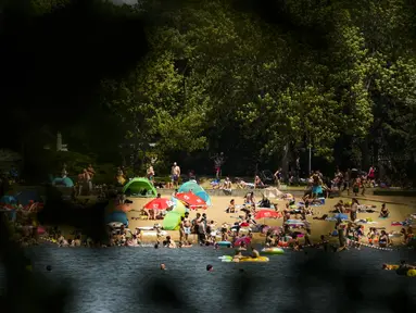 Orang-orang menikmati hari musim panas di danau Orankesee di Berlin, Jerman, Minggu (19/6/2022). Orang-orang berbondong-bondong ke taman dan kolam renang di seluruh Eropa Barat untuk sedikit mendinginkan tubuh mereka dari gelombang panas awal. (AP Photo/Markus Schreiber)