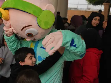 Seorang anak memeluk seseorang yang mengenakan kostum saat para sukarelawan menyiapkan bingkisan makanan dan manisan Idulfitri untuk keluarga pengungsi yang merayakan hari raya jauh dari rumah mereka, di sebuah universitas negeri yang diubah menjadi tempat penampungan setelah serangan udara Israel di Beirut, Lebanon, Jumat 20 Maret 2026. Perayaan Hari Raya Idulfitri 1447 Hijriah di sebuah Universitas Negeri yang diubah menjadi tempat penampungan warga setelah serangan udara Israel di Beirut, Lebanon, berlangsung penuh keceriaan. (AP Photo/Hassan Ammar)