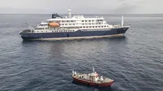 Pemandangan udara sebuah kapal ambulans yang membawa awak yang mengenakan pakaian pelindung bahan berbahaya (hazmat suit) saat mereka mendekati pintu kemudi di sisi kanan kapal pesiar MV Hondius, ketika kapal tersebut berhenti di lepas pelabuhan Praia, ibu kota Tanjung Verde, Selasa 5 Mei 2026. Kapal pesiar MV Hondius saat ini masih tertahan di lepas pantai Praia, Tanjung Verde. (Foto oleh AFP)