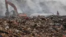 Petugas pemadam kebakaran dan alat berat  berusaha memadamkan api di Tempat Pembuangan Akhir (TPA) Jatiwaringin, Kabupaten Tangerang, Banten, Jumat (03/07/2026). (Merdeka.com/ Arie Basuki)