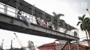 Petugas Satpol PP mencopot alat peraga kampanye (APK) berupa spanduk caleg di JPO kawasan Gambir, Jakarta, Sabtu  (22/12). PenertiBan spanduk APK dilakukan karena melanggar aturan pemasangan dari komisi pemilihan umum. (Liputan6.com/Faizal Fanani)