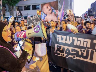 Seorang wanita berbicara melalui megafon ketika para aktivis Israel berbaris dengan membawa karung-karung tepung menuju markas besar Kementerian Pertahanan Israel di Tel Aviv pada 22 Juli 2025. (Jack GUEZ/AFP)